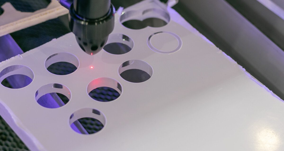 Details of an industrial CNC laser cutting machine. Drilling holes in plexiglass panel with a hot plasma pinhead. Automation concept, robotic arm, future jobs concept.