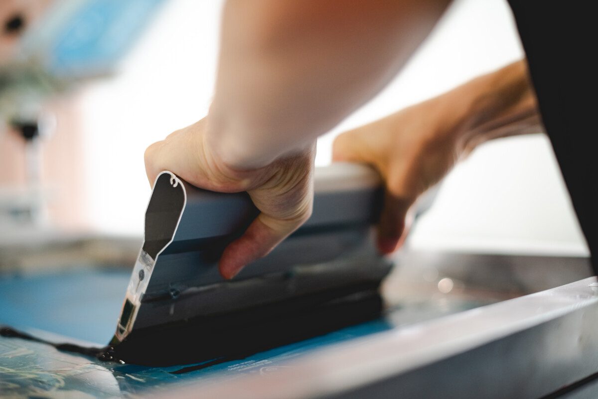 Cropped view of craftsman working on screen printing machine in